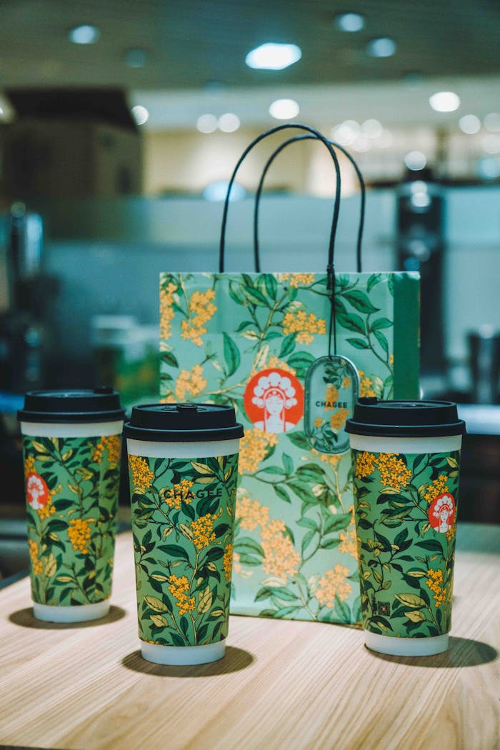 Elegant floral coffee cups and matching bag in a modern setting.